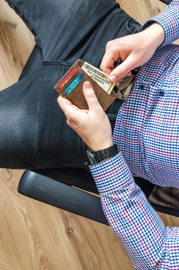 Close-up of a man in casual attire holding a wallet and checking his credit cards indoors.